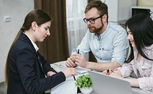 Two women analyzing information on a laptop screen, demonstrating teamwork and communication skills.
